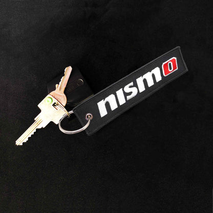 A nismo jet tag holding two keys on a black gackground
