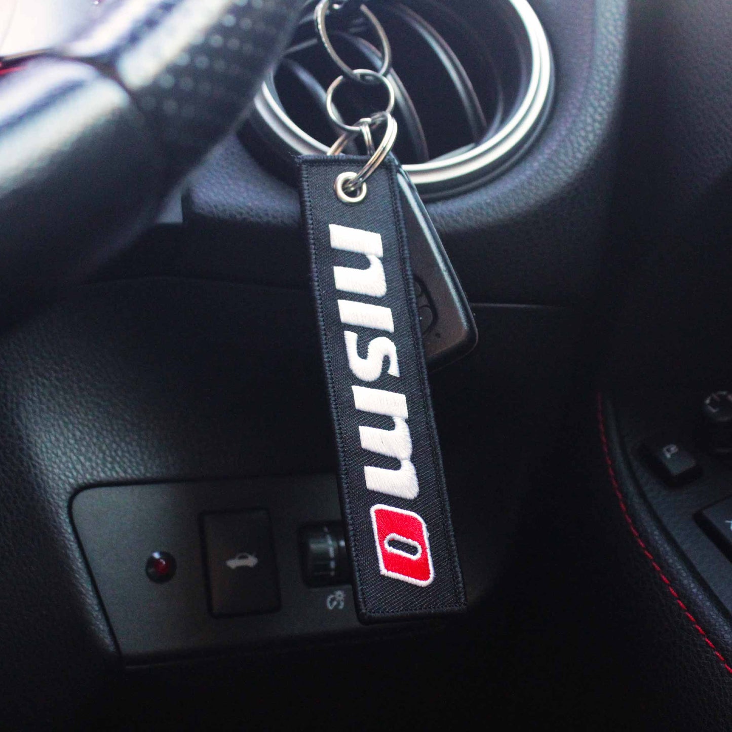 A nismo jet tag hung on a steering wheel control stick