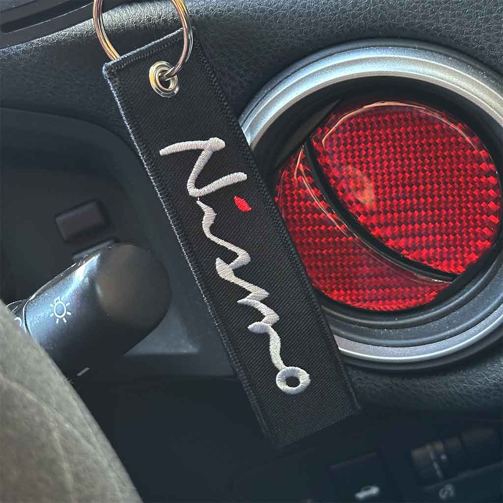 A black Nissan Nismo keychain hung in a GTR skyline