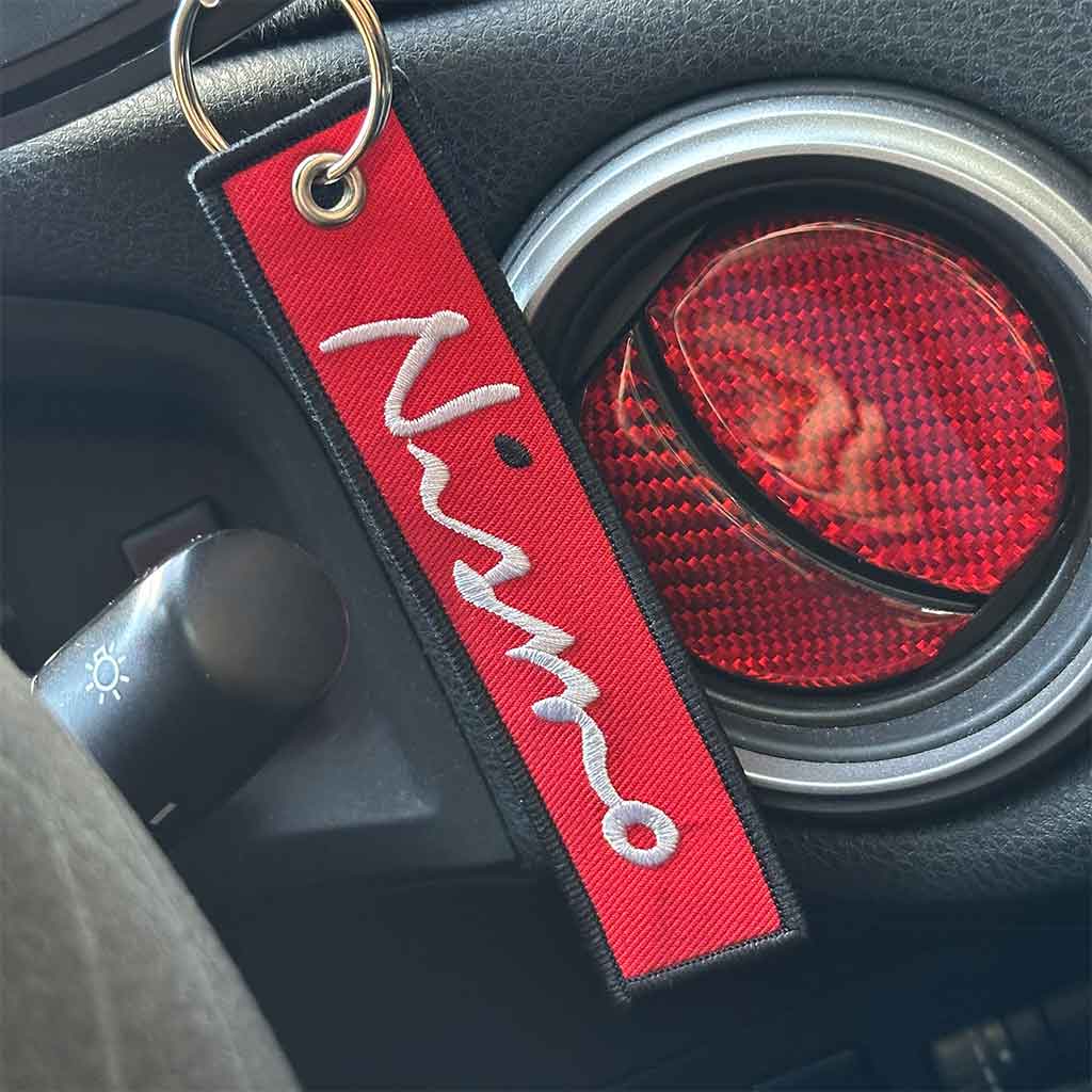 A red Nissan Nismo keychain hung in a GTR skyline