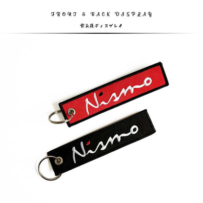 Display of front of back of a Nissan Nismo keychain on a white background