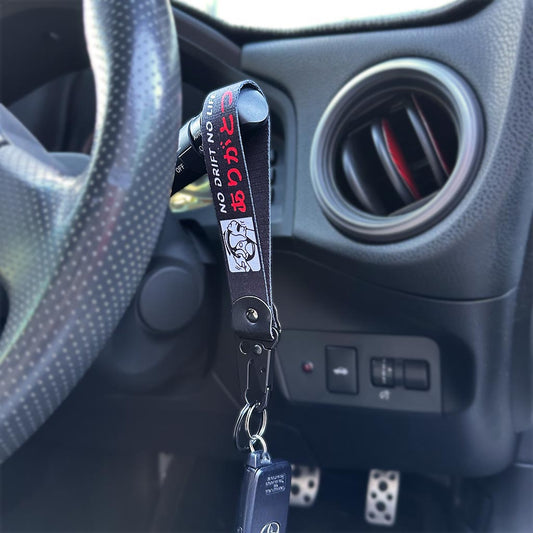 A No Drift No Life lanyard hanging on a steering wheel control stick holding a Toyota car key