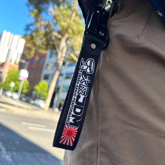 A Osaka Kanjo Performance lanyard in a pocket of a man standing in an open area