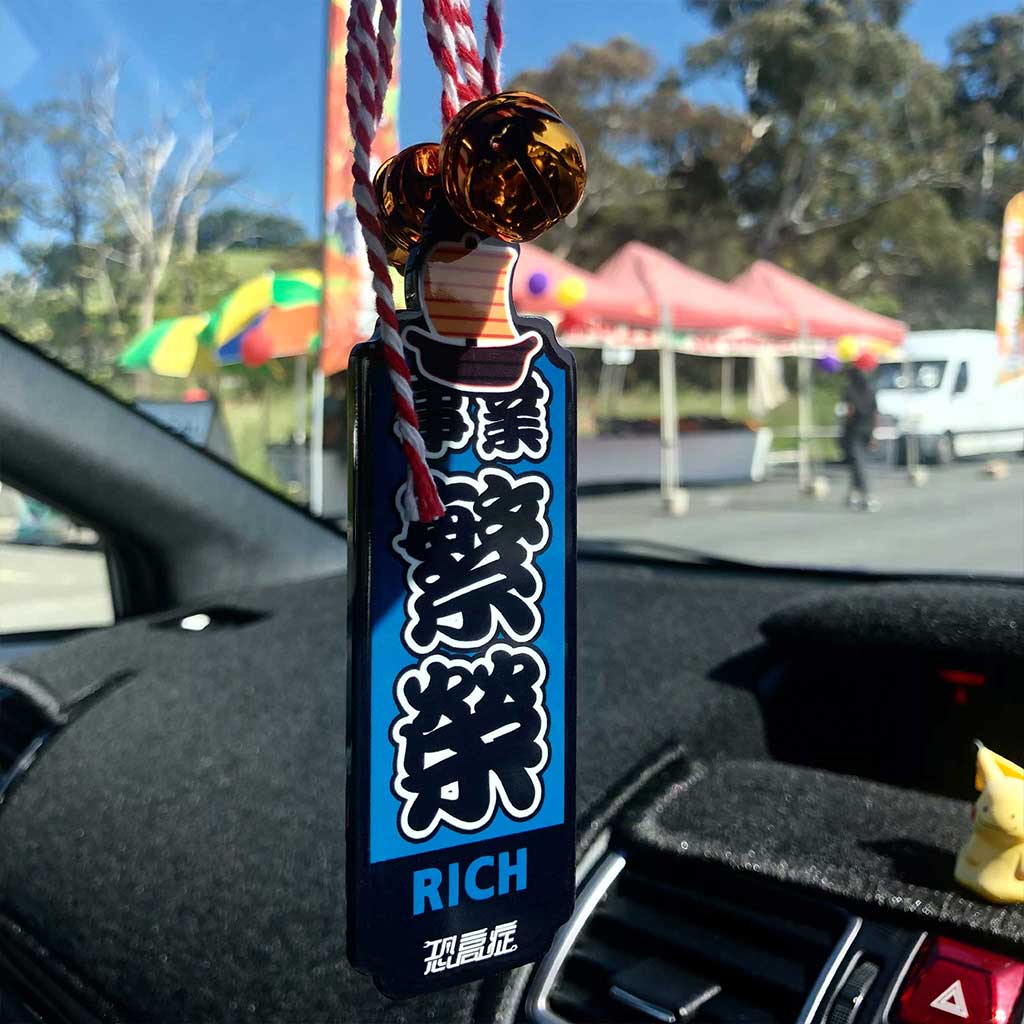 A blue Japanese charm meaning 'career prosperity' hung on a car's rearview mirror