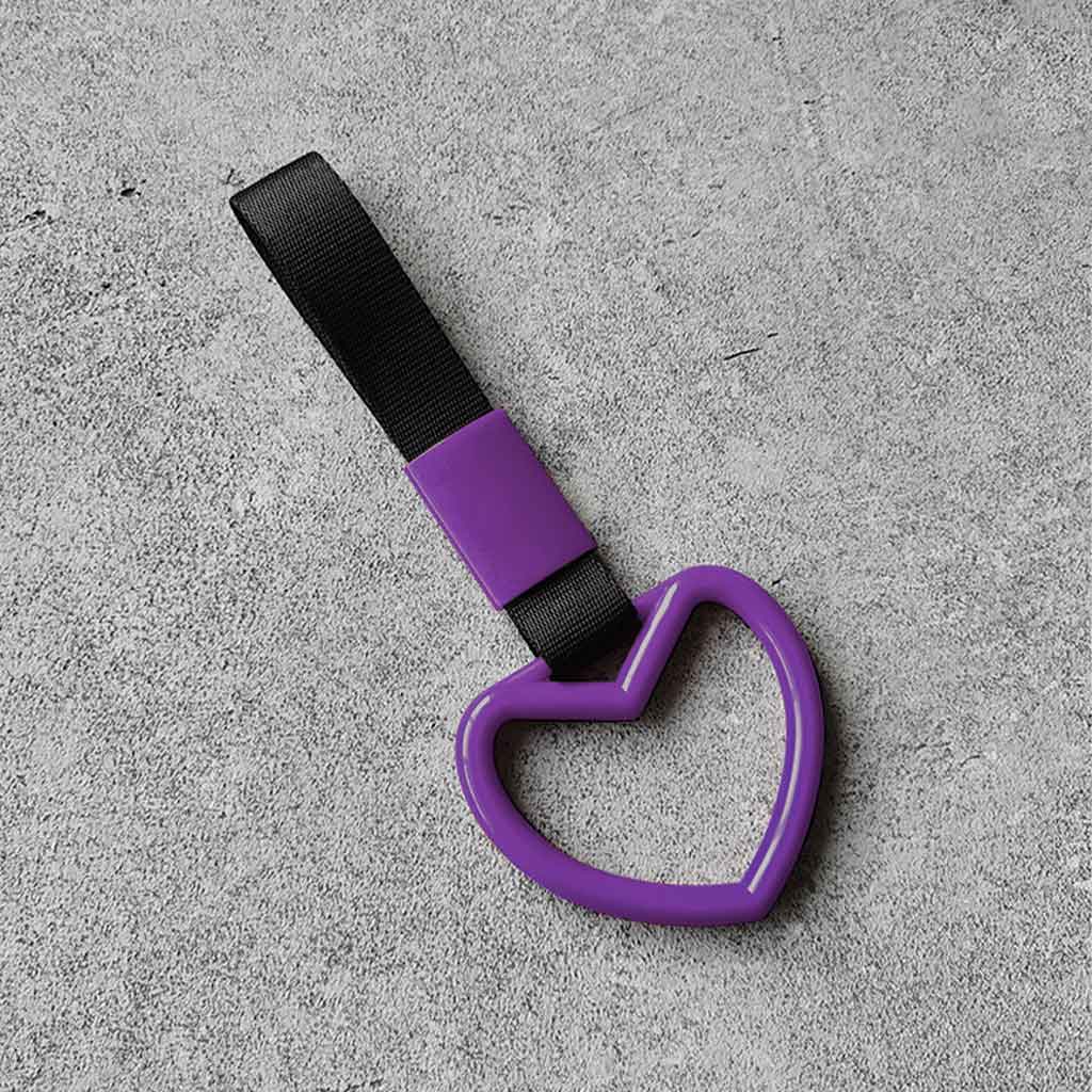 A purple heart tsurikawa with black handle strap flat laid on a concrete floor