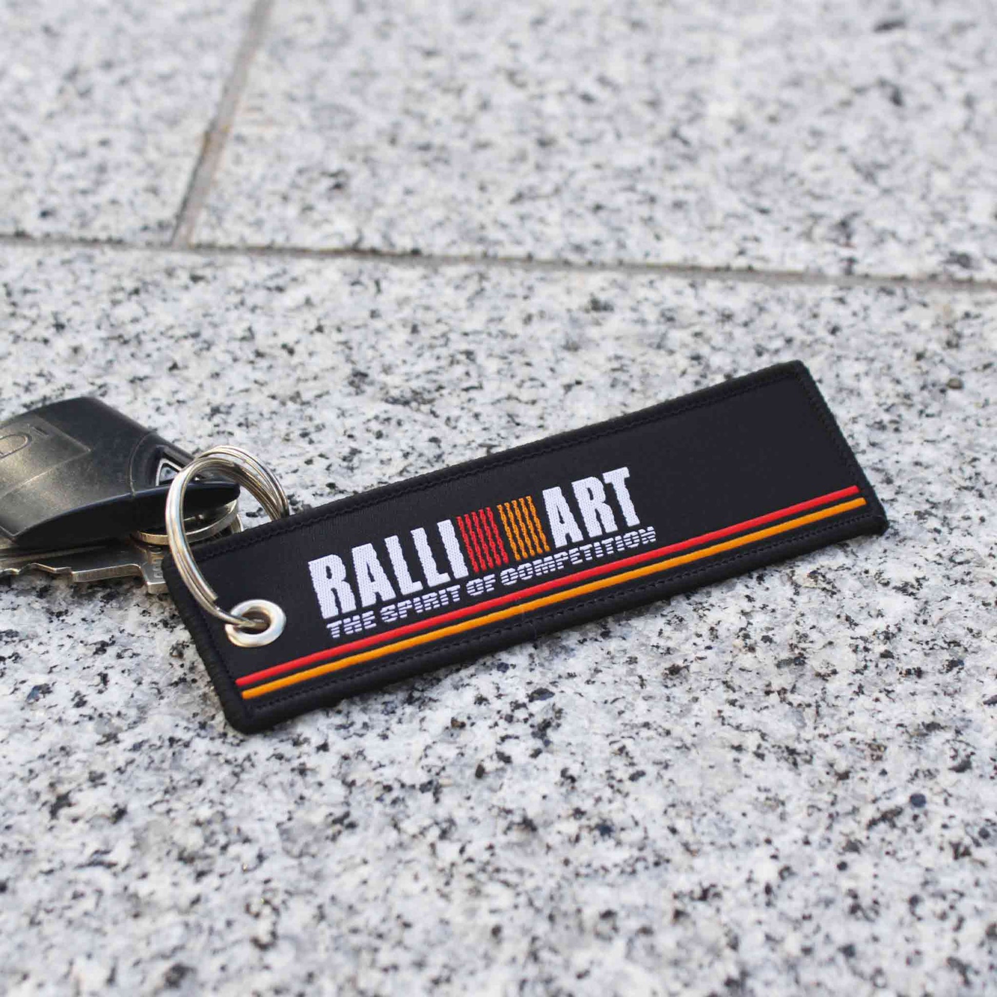 A ralli-art lanyard holding a fob placed on a marble floor