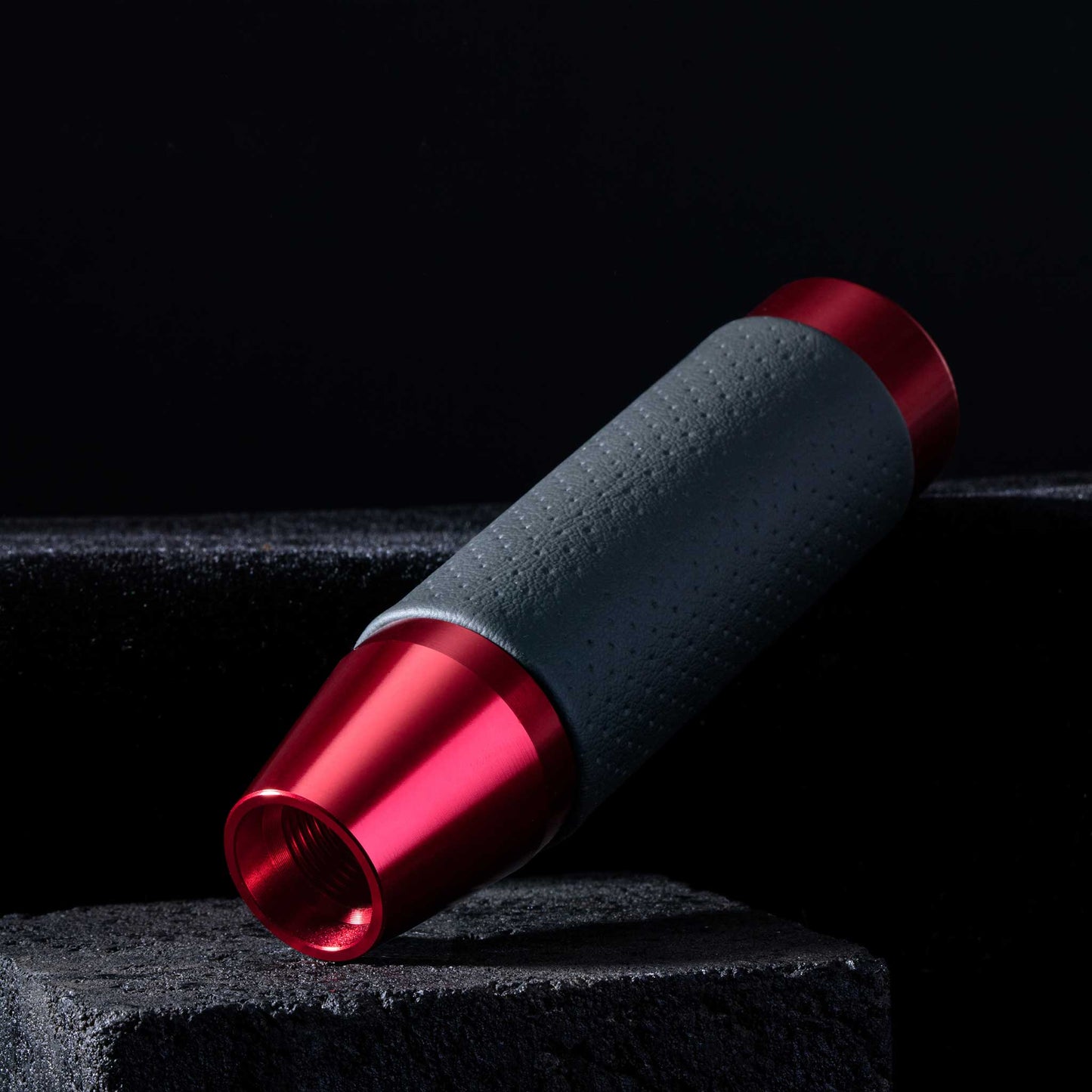 A red leather shift knob are leaning towards stone stairs on a black background