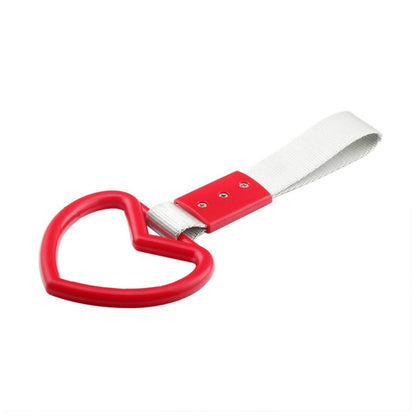 A red heart tsurikawa with silver handle strap flat laid on a white background