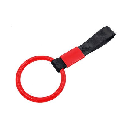 A red ring tsurikawa with black handle strap flat laid on a white background