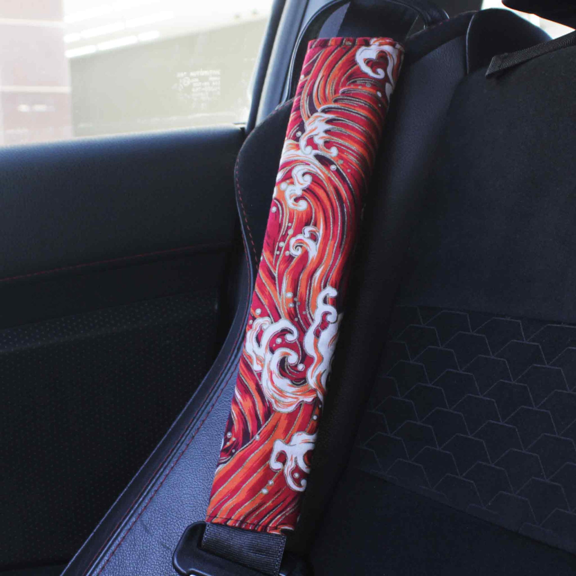 A seat belt cover with red great waves pattern installed on a Toyota 86's seat belt