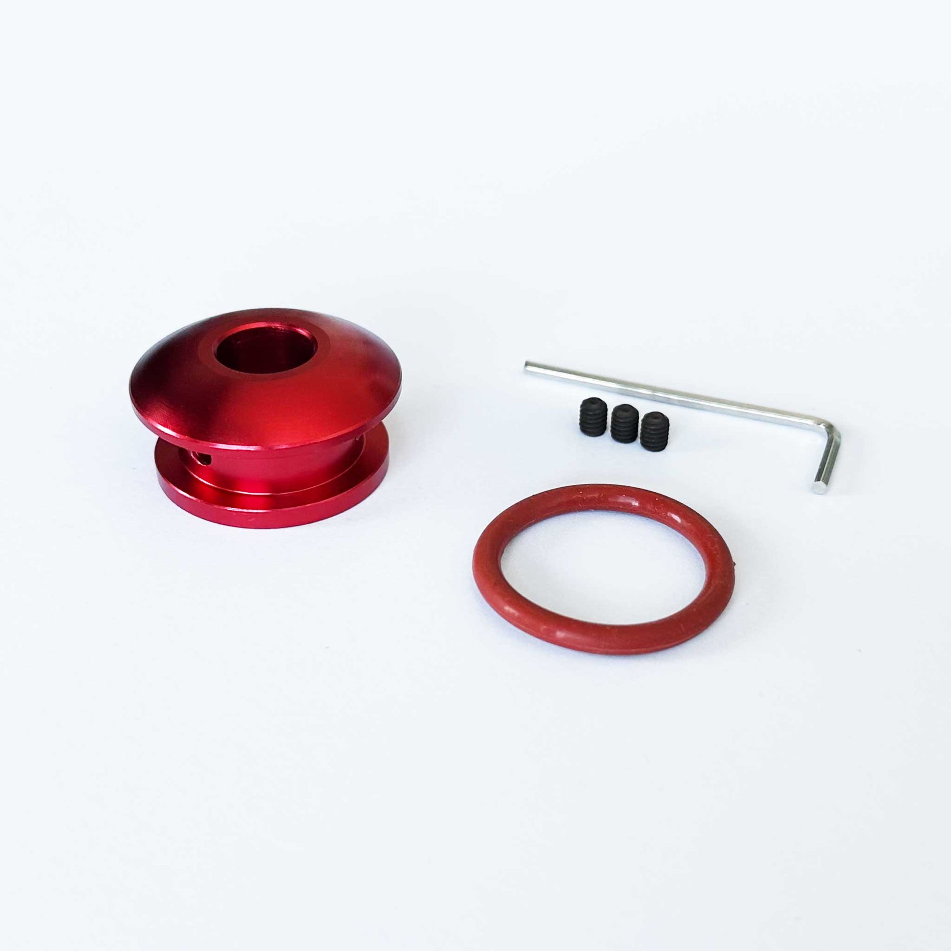 A red non-threaded boot retainer is standing upright on a white background with installation tools beside it