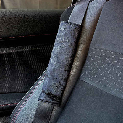 A piece of JDM all-black seat belt cover featuring Japanese flying cranes and flowers installed in a Toyota 86