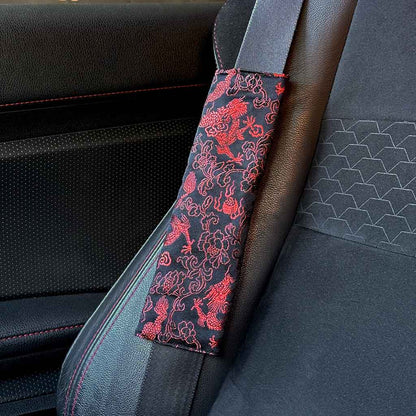 A piece of JDM seat belt cover featuring red Eastern Dragons installed in a Toyota 86