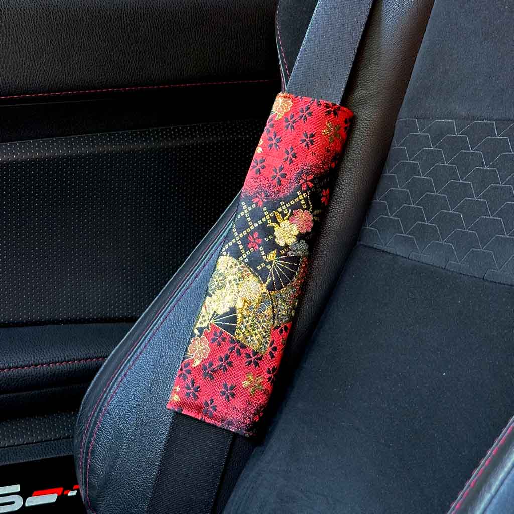 A piece of JDM seat belt cover featuring golden cherry blossoms and Japanese fans installed in a Toyota 86