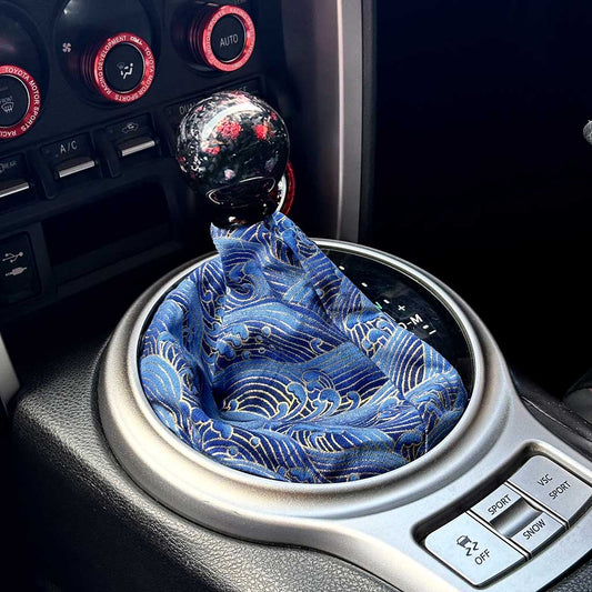 A cool JDM shift boot featuring blue Japanese waves installed in an automatic Toyota 86, with a red carbon fibre shift knob on top