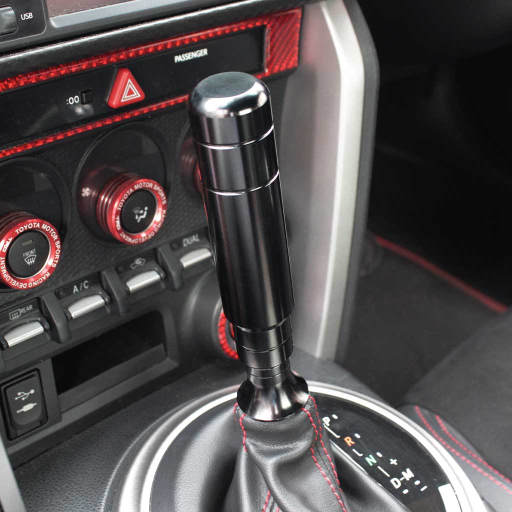 A black aftermarket shift knob with a boot retainer underneath installed in an automatic GT86
