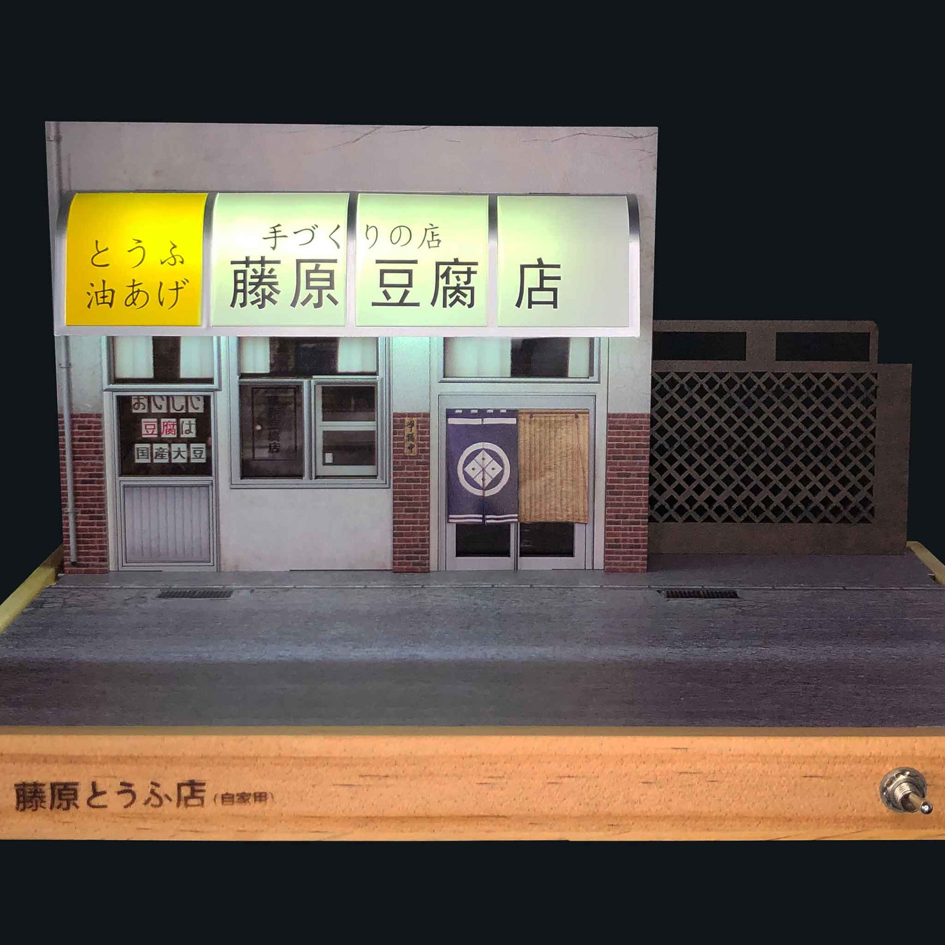 Front of a Fujiwara tofu shop on a wooden base with black background