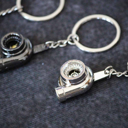 A silver turbo keychain being focused with a black one on side