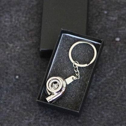 A silver turbo keychain in a gift box on a dark grey background