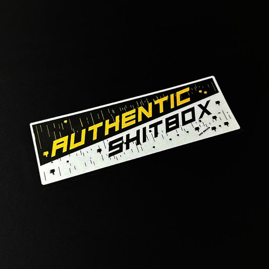 An authentic shitbox JDM slap sticker flat laid on a black background