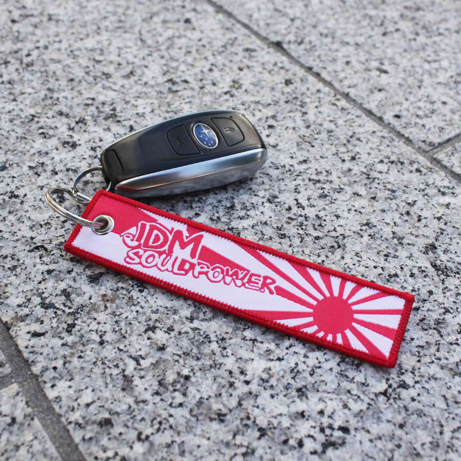 A red and white JDM soul power jet tag holding a Subaru car key on a marble floor