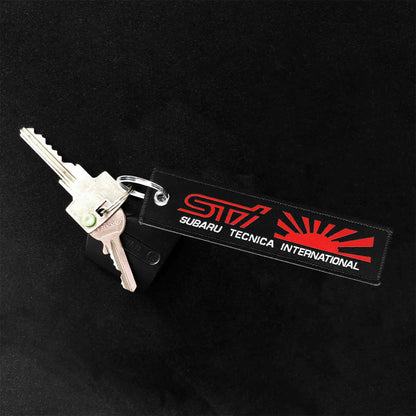 A black sti jet tag with red and white characters as well as the rising sun holding two keys on a black background