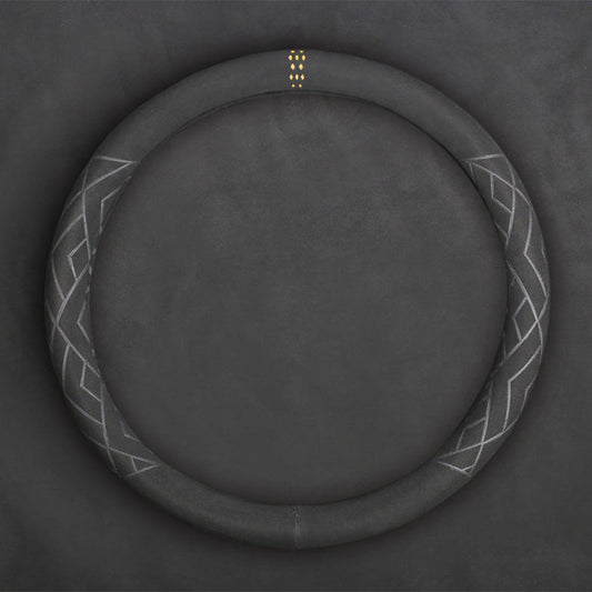 A grey suede steering wheel cover in O shape with yellow mark flat laid on a grey background