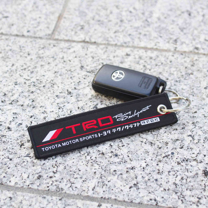 A TRD jet tag holding a Toyota car key on a marble floor