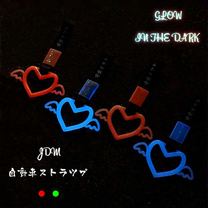 Four glow-in-the-dark tsurikawas flat laid on the concrete ground at night and showing blue and red