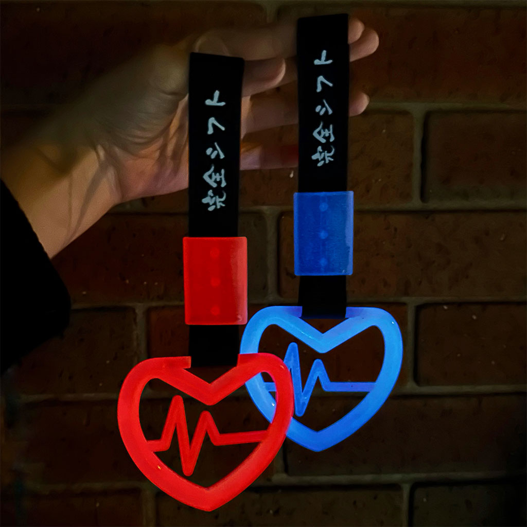 A hand holding two tsurikawas at night and they glow blue and red