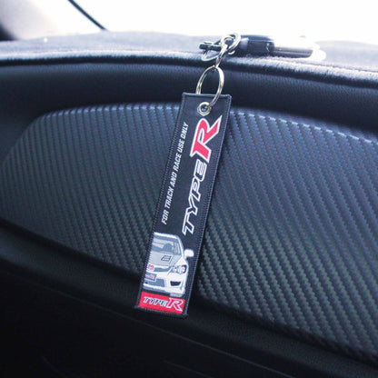 A Honda type-r jet tag hung on a car's center console which is made of carbon fibre
