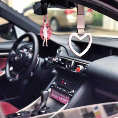 A white heart tsurikawa hung in a Lexus car, where an anime decoration hung on the rearview mirror
