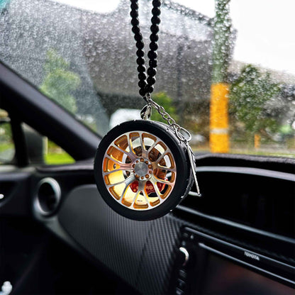 A yellow BBS air-freshener hung on a car's rear mirror. The car is parked next to some trees, and it seems that it's raining